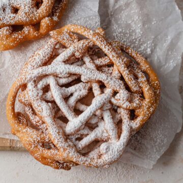 close up shot showing details of crisp, fried funnel cake and the dusting of powdered sugar on top