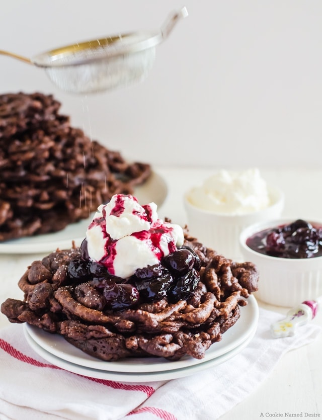 chocolate funnel cake with toppings being dusted with powdered sugar