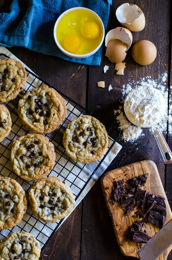 overhead of chocolate chip cookies cooling on wire rack on wood table next to ingredients