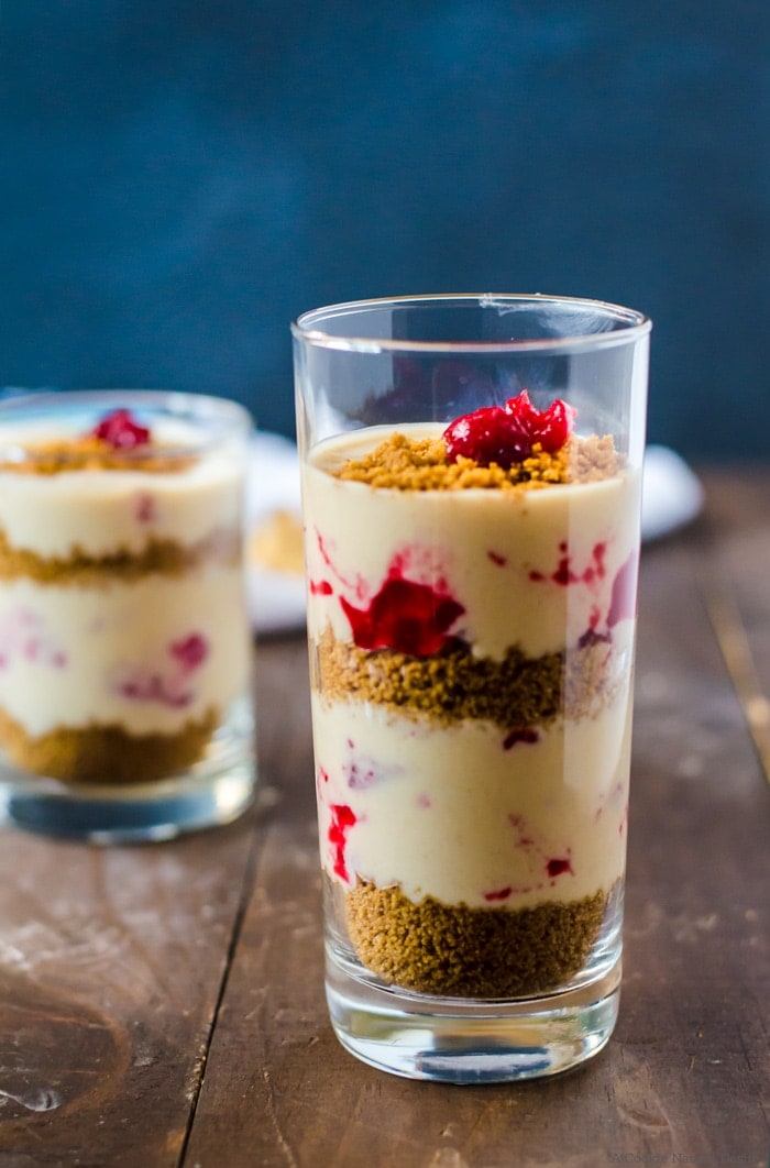 A creamy vegan no-bake cheesecake parfait with cranberry swirl and gingersnap crumble