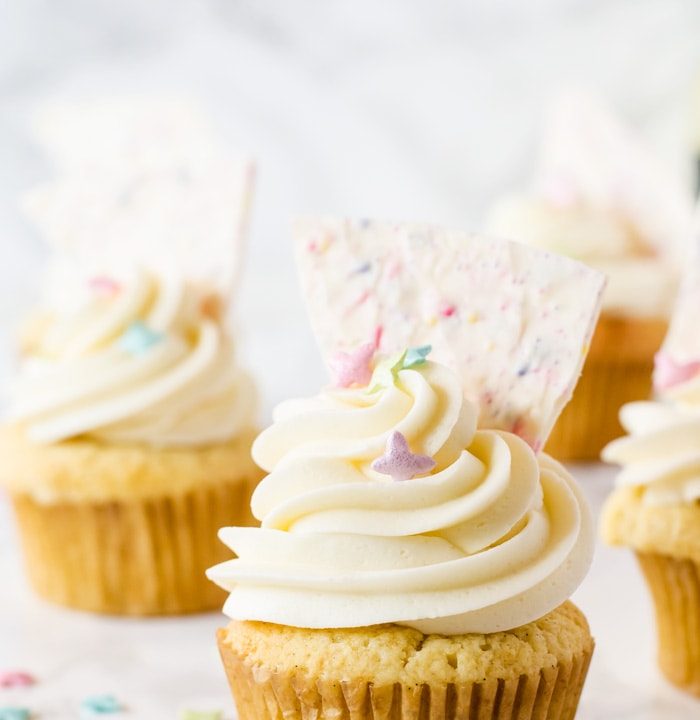 Celebrate Spring with these heavenly vanilla cupcakes filled with a bright lemon curd and topped with a fun sprinkle-filled white chocolate bark!