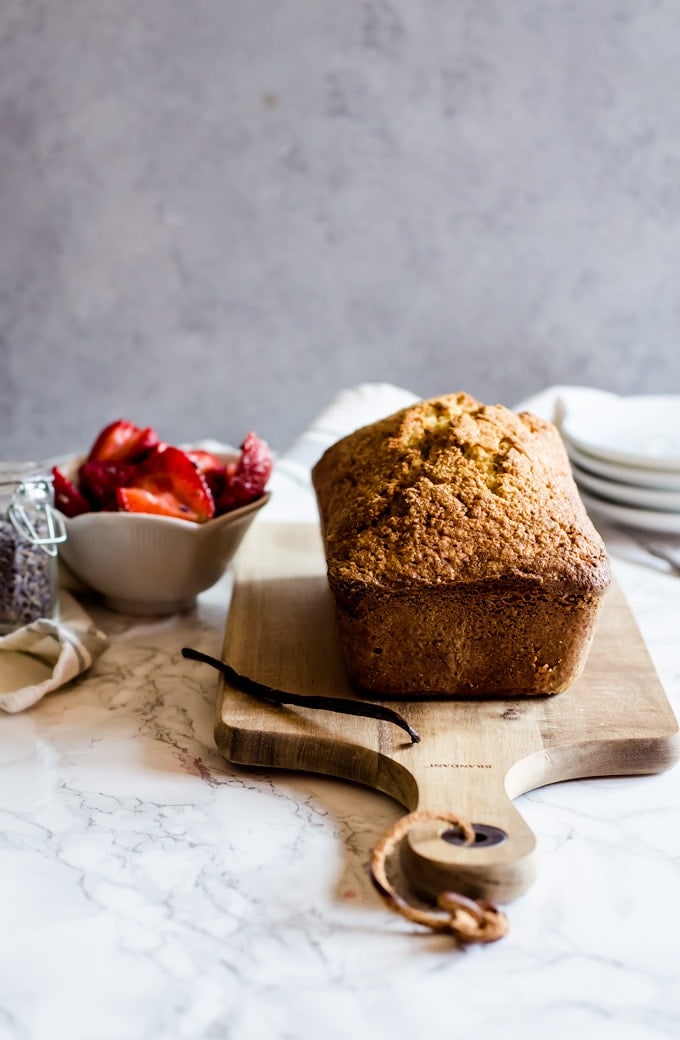 pound cake on wood board next to strawberries in bowl