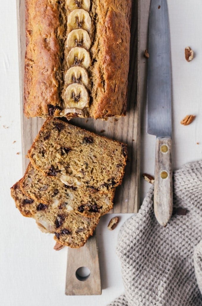 Loaf of bread on cutting bord with slices being cut out