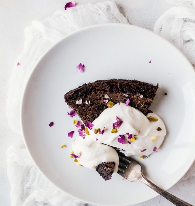 A simple sweet chocolate olive oil cake with pistachios, rose, and a light cardamom whipped cream