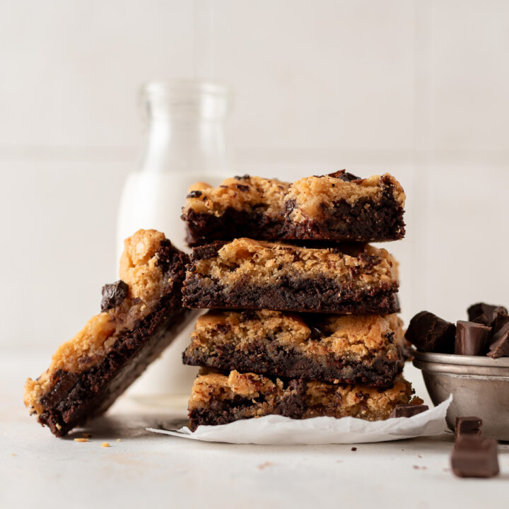 stacked brookies next to glass of milk and chocolate chips in bowl