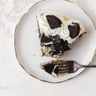 An ocerhead photo of a slice of No-bake Oreo Cheesecake on a plate with a forkful of cheesecake