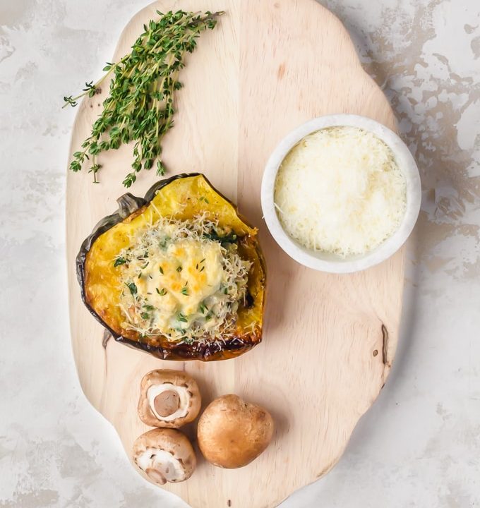 overhead shot turkey stuffed acord squash on chopping board with cheese, mushrooms, and thyme