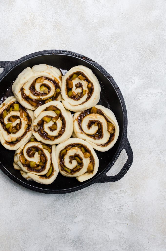 cinnamon rolls with apples in pan before baking