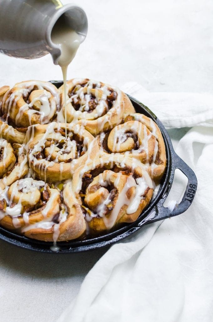 cinnamon rolls being drizzled with icing