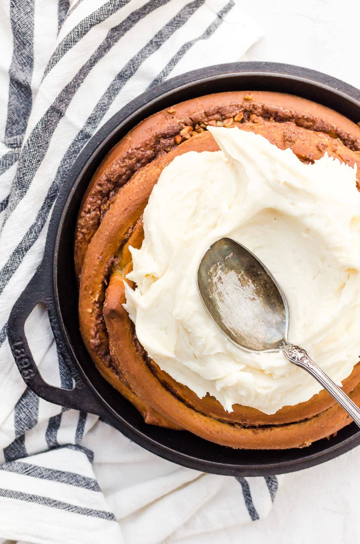 overhead giant cinnamon roll cream cheese icing spread spoon