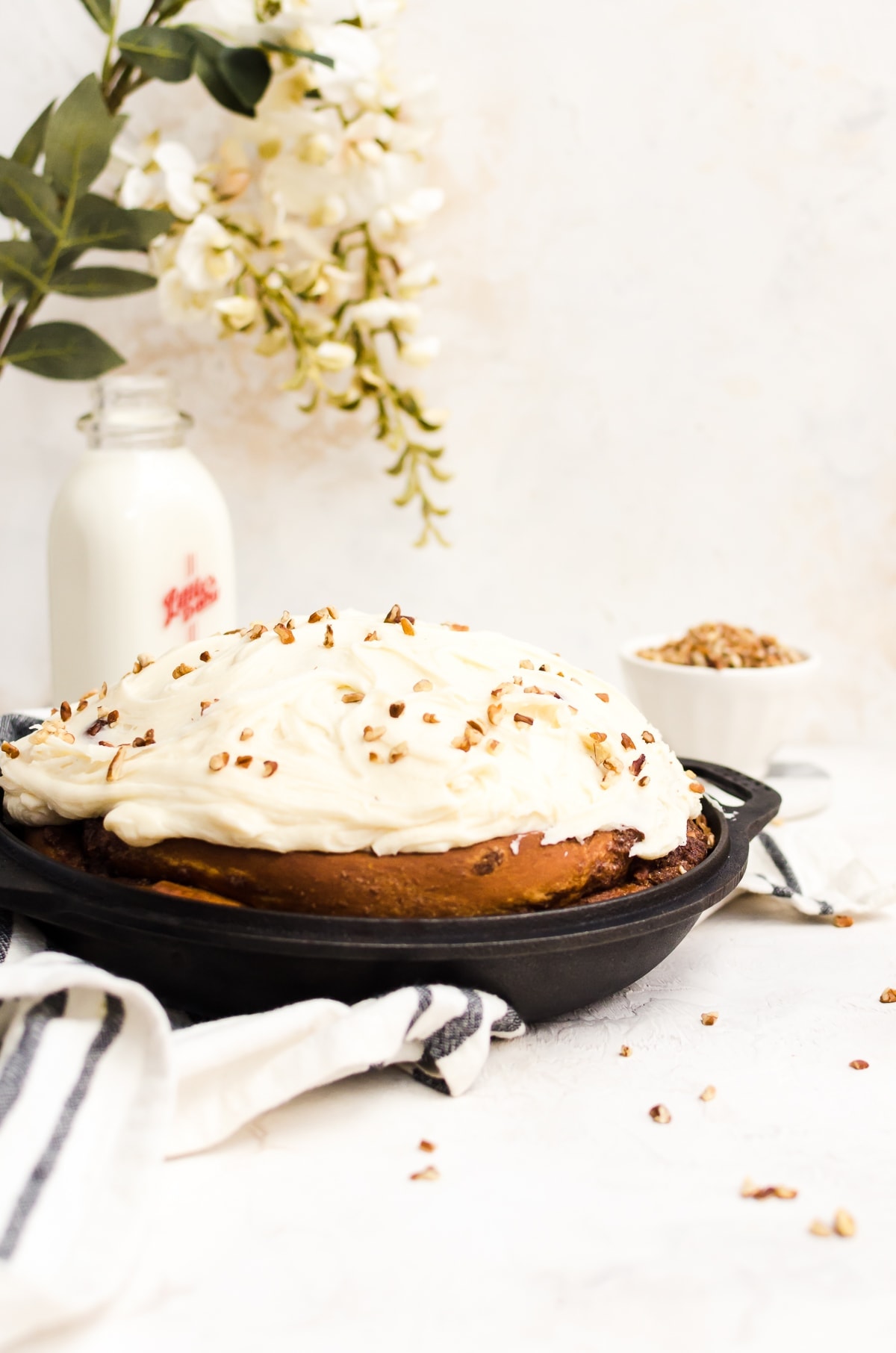 giant cinnamon roll with frosting in cast iron pan