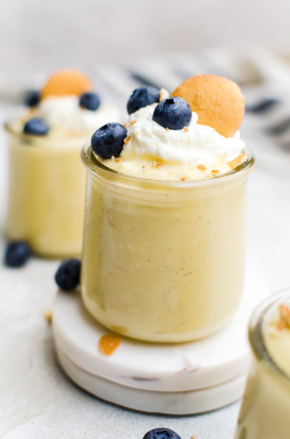 close up homemade vanilla pudding in a cup with berries and whipped cream