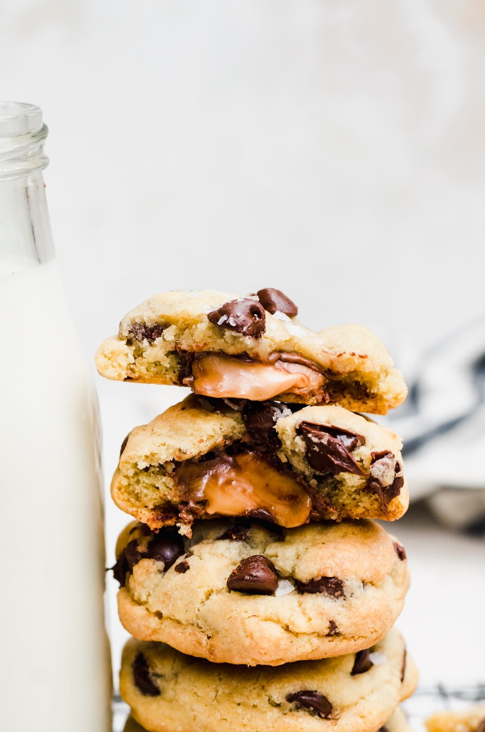 close up salted caramel stuffed chocolate chip cookies stacked with gooey caramel oozing out