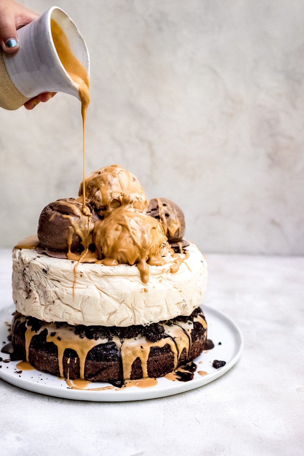 chocolate peanut butter ice cream cake being drizzled with peanut butter sauce
