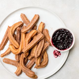 homemade churros on white plate with jam