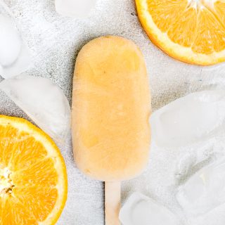 close up orange creamsicle popsicle with ice and orange slices
