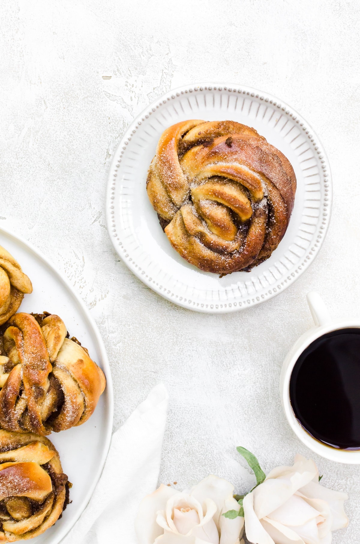 Overhead cardamom bun on plate next to coffee in mug