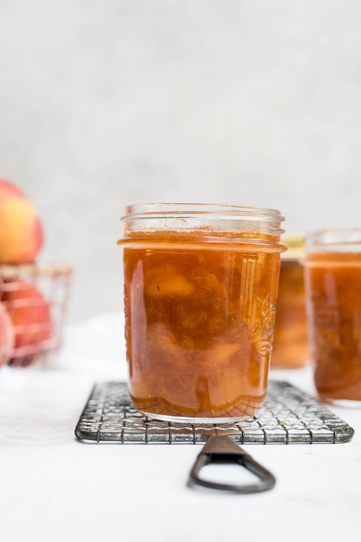 peach jam in a jar with peaches in the background