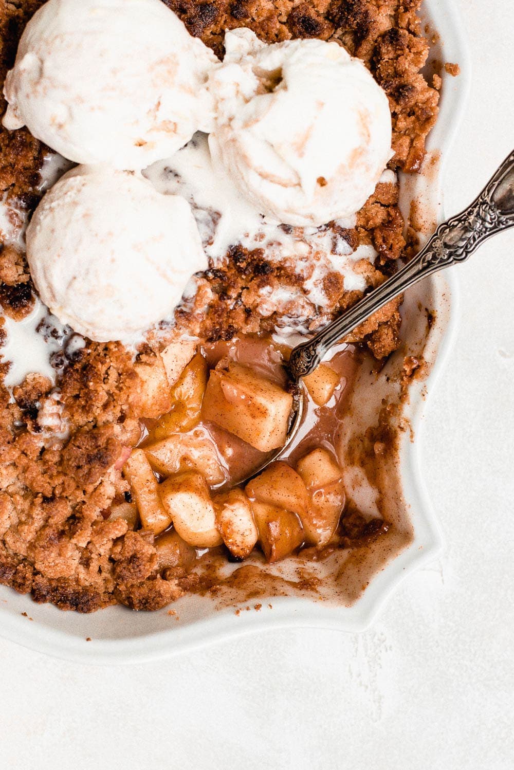 baking dish showing cooked apples and crumble topped with ice cream