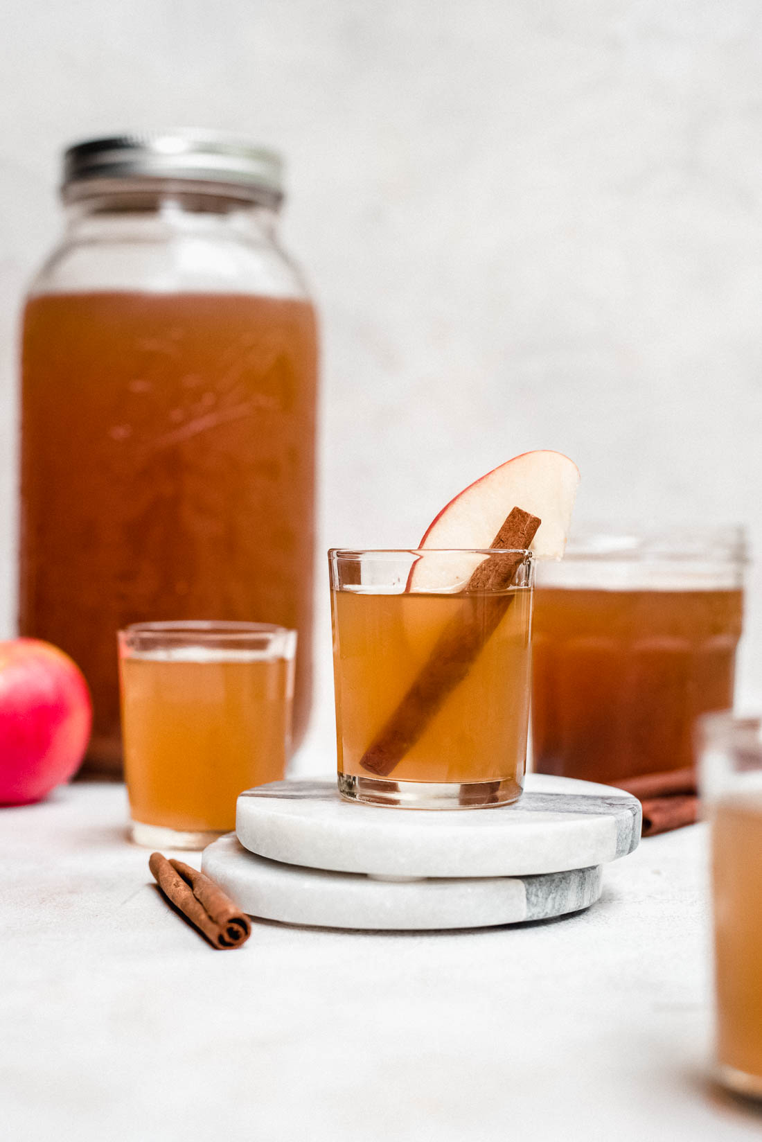 apple pie moonshine in shot glasses and mason jar with cinnamon and apples