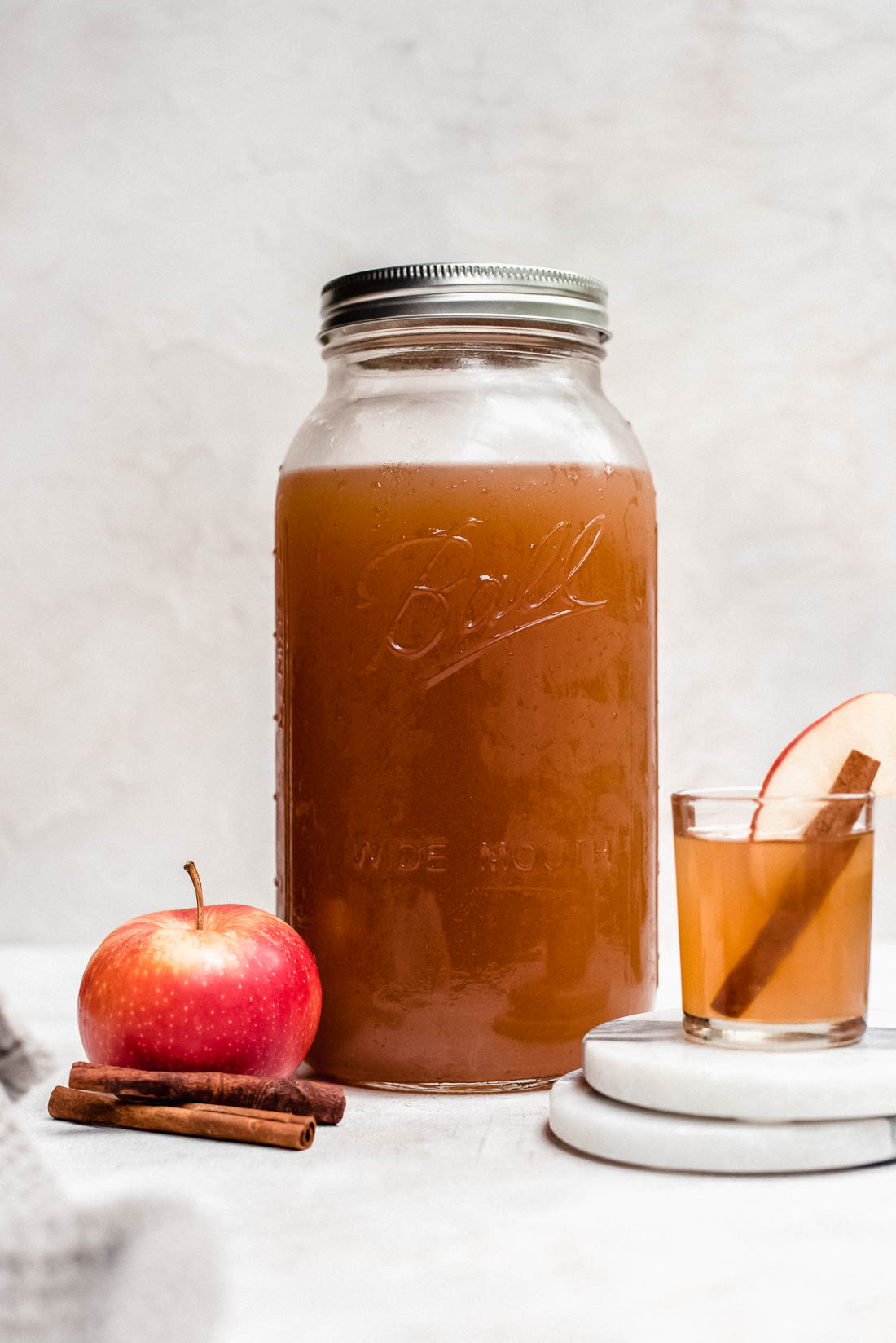 apple pie moonshine in mason jar with apples and cinnamon stick