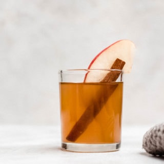 apple pie moonshine in shot glass with apple slice and cinnamon stick