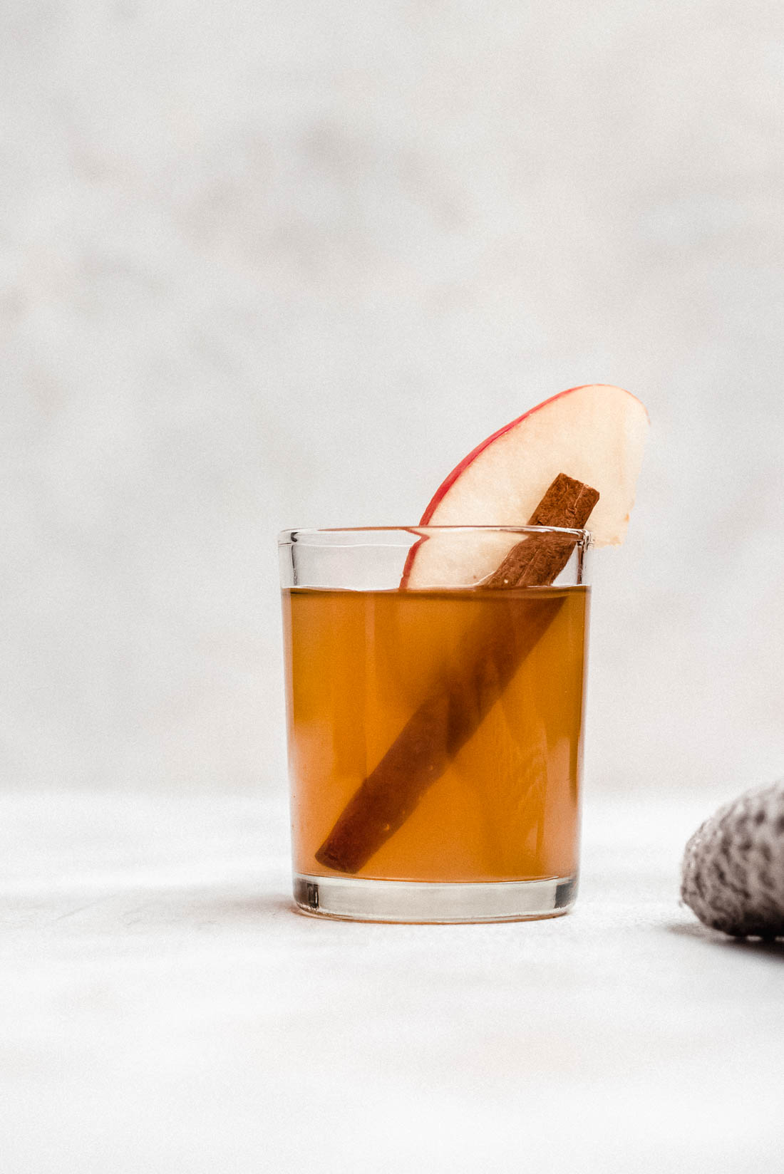 apple pie moonshine in shot glass with apple slice and cinnamon stick