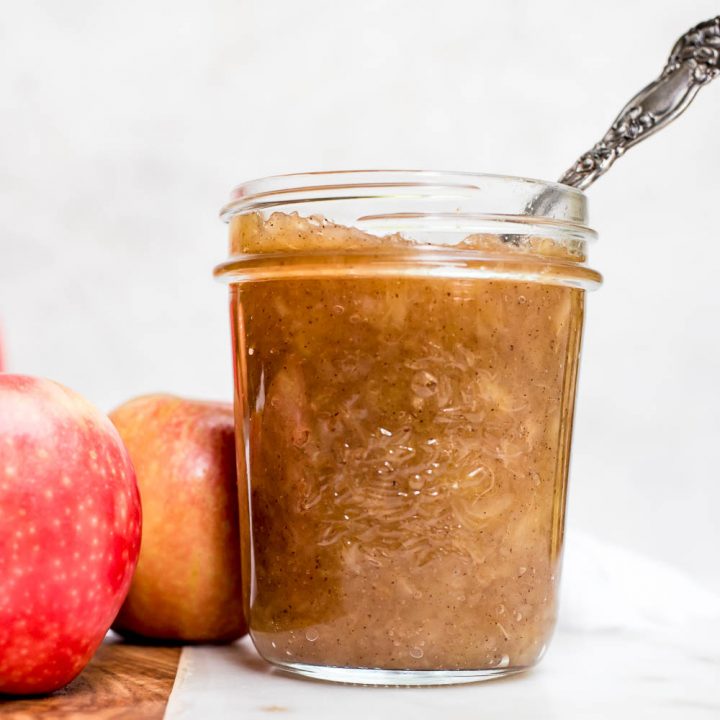homemade apple sauce in jar with spoon by whole apples