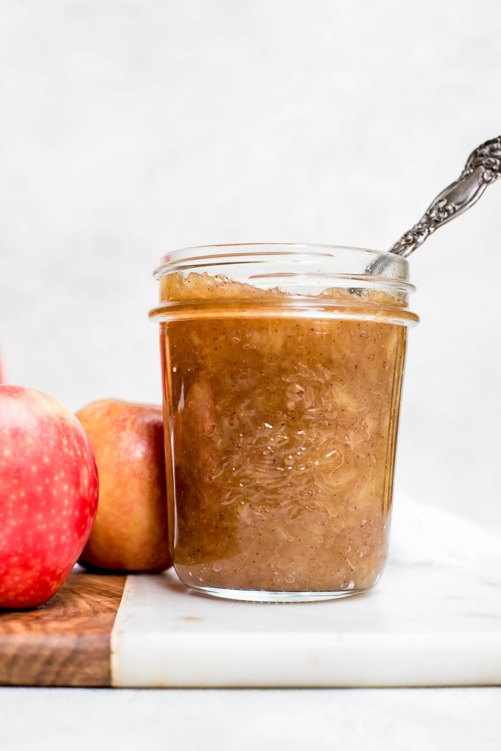 homemade applesauce in jar with spoon by whole apples