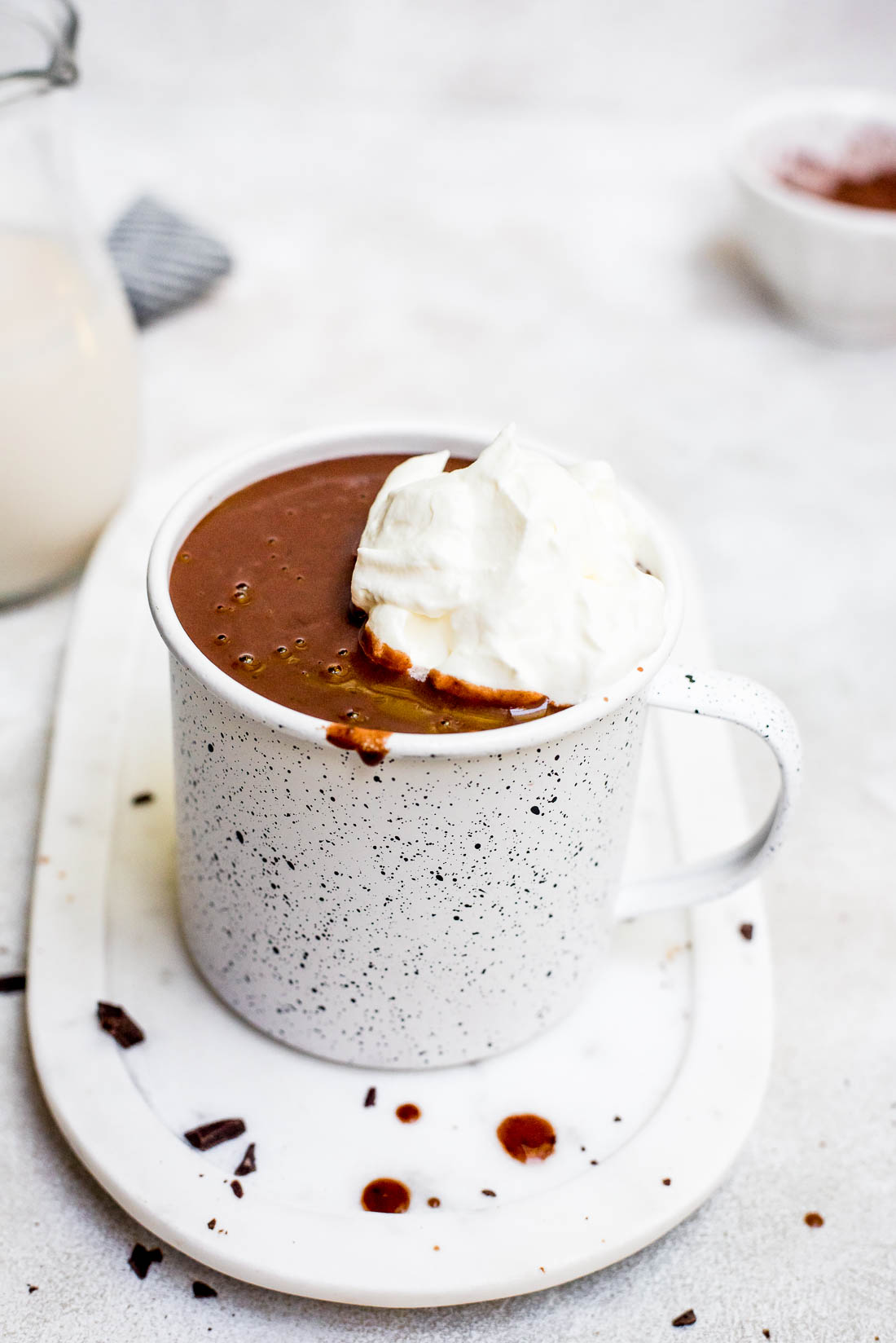 hot chocolate in a mug with whipped cream on marble coaster