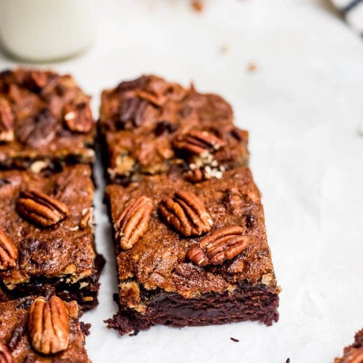 pecan pie brownies on parchment with glass of milk
