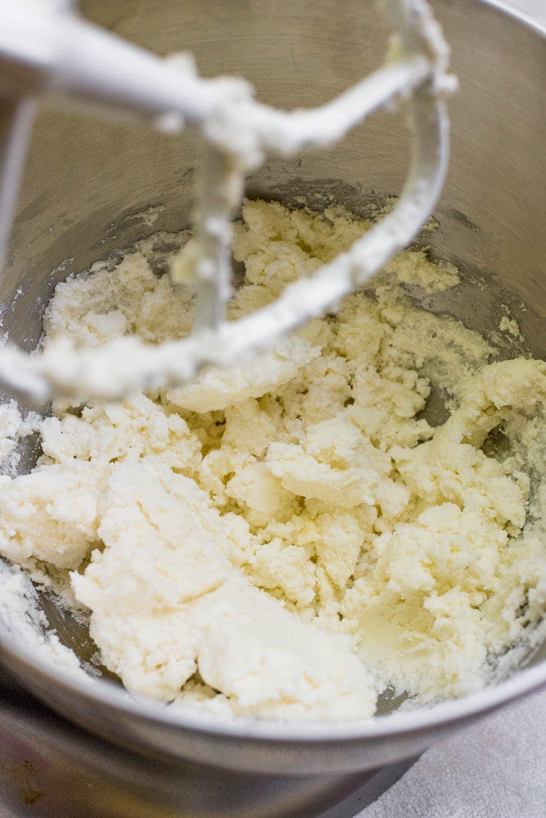 ingredients for buttercream being mixed together in bowl