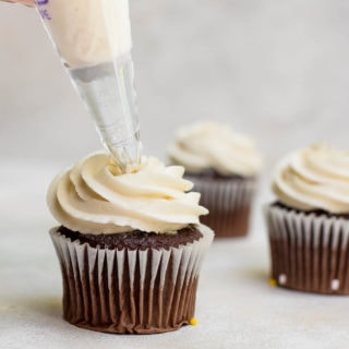 frosting being piped on cupcake