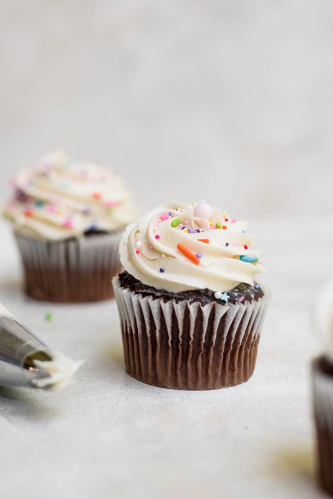 frosting on cupcake being topped with sprinkles