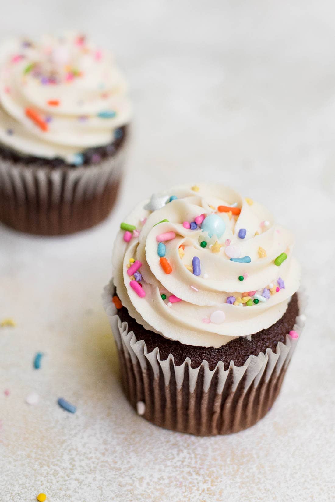 close up of cupcakes with vanilla buttercream frosting and sprinkles