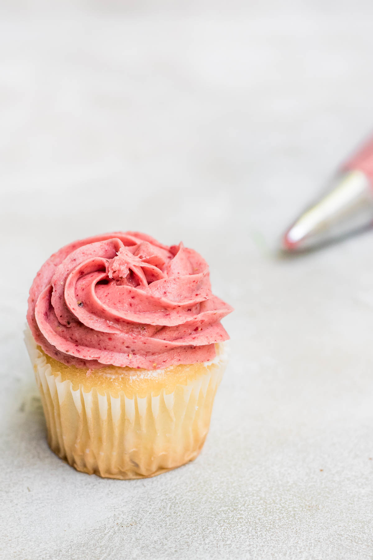 cupcake with frosting and piping bag in background