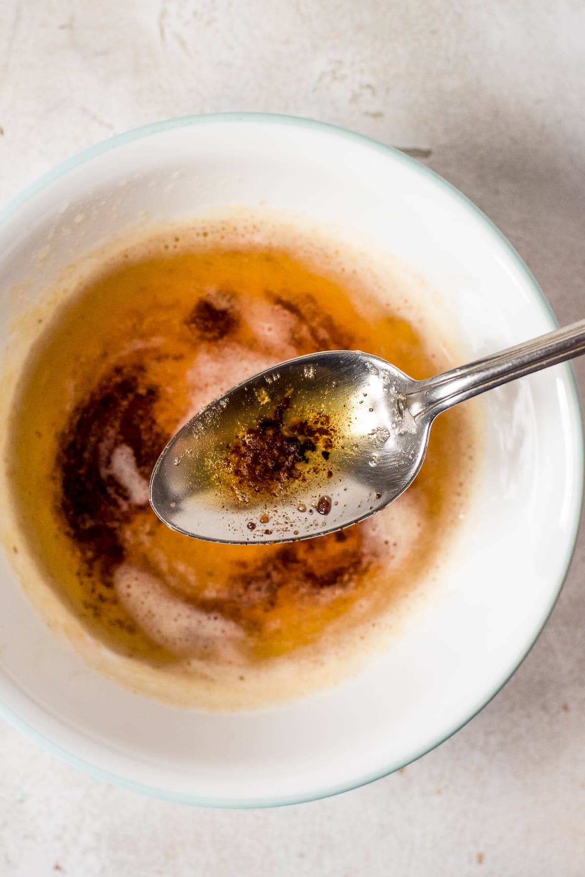 close up brown butter with flecks of caramelized milk solids on spoon over bowl