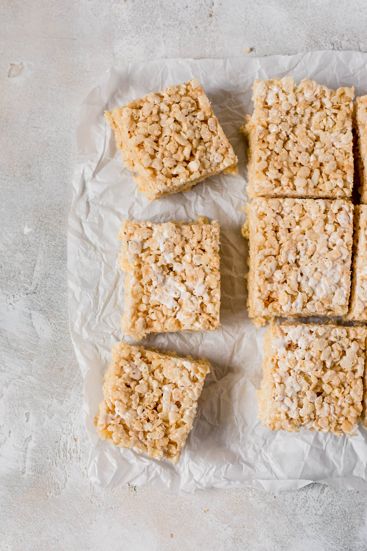 rice krispie treats being cut into squares on parchment paper
