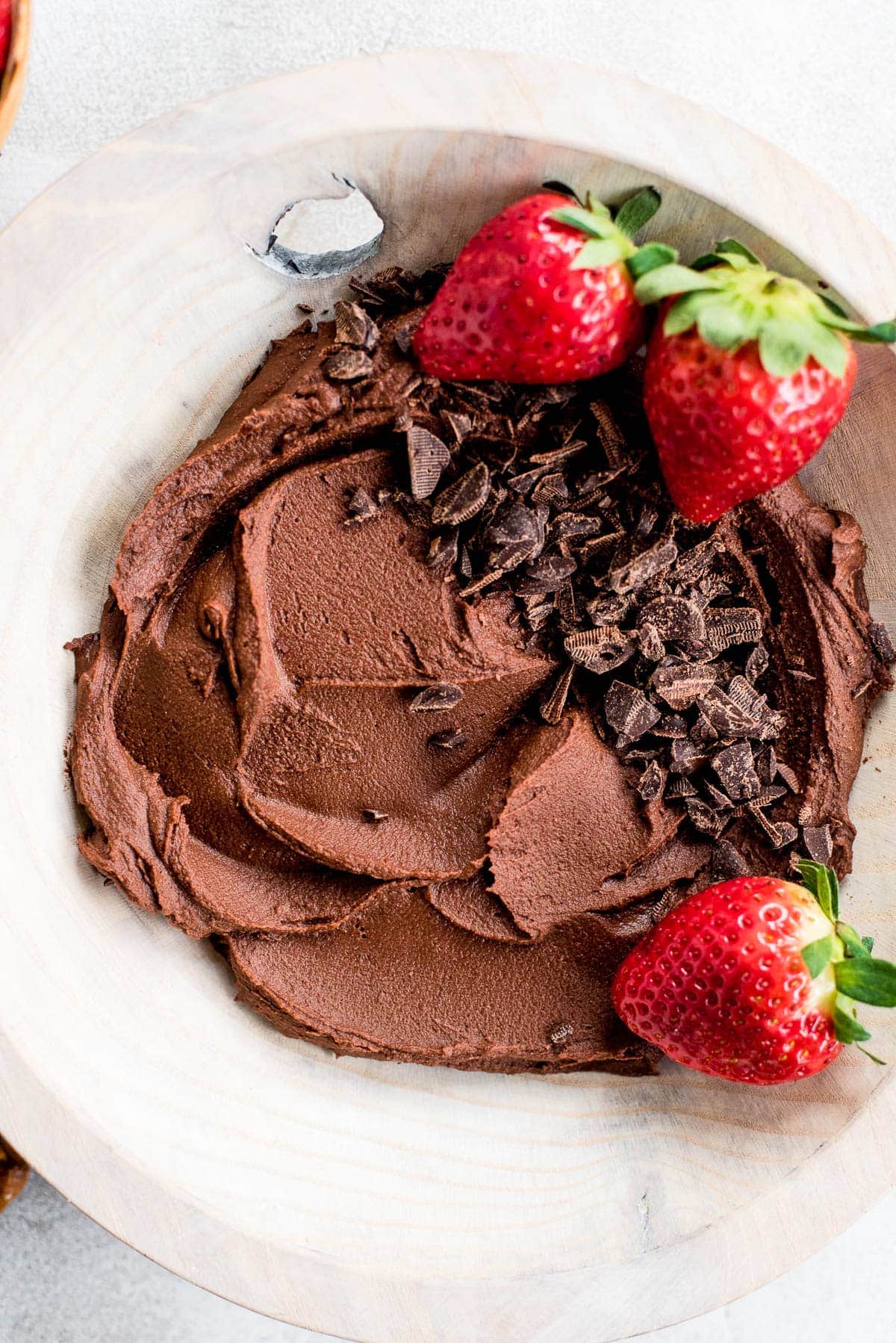 close up chocolate hummus in bowl topped with chocolate and strawberries