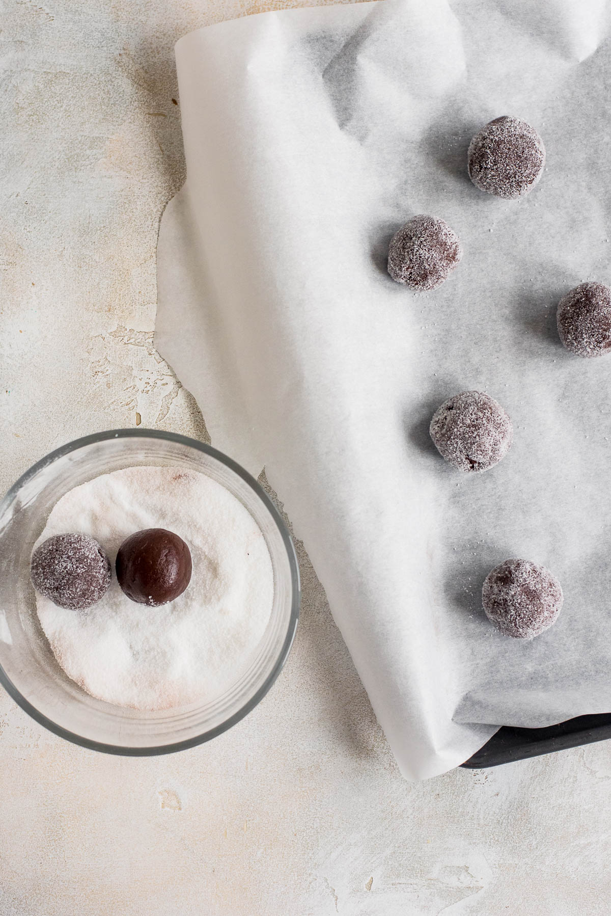 balls of cookie dough being rolled in sugar