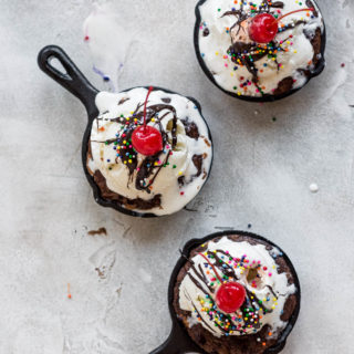 mini skillets topped with ice cream, chocolate syrup, and cherries