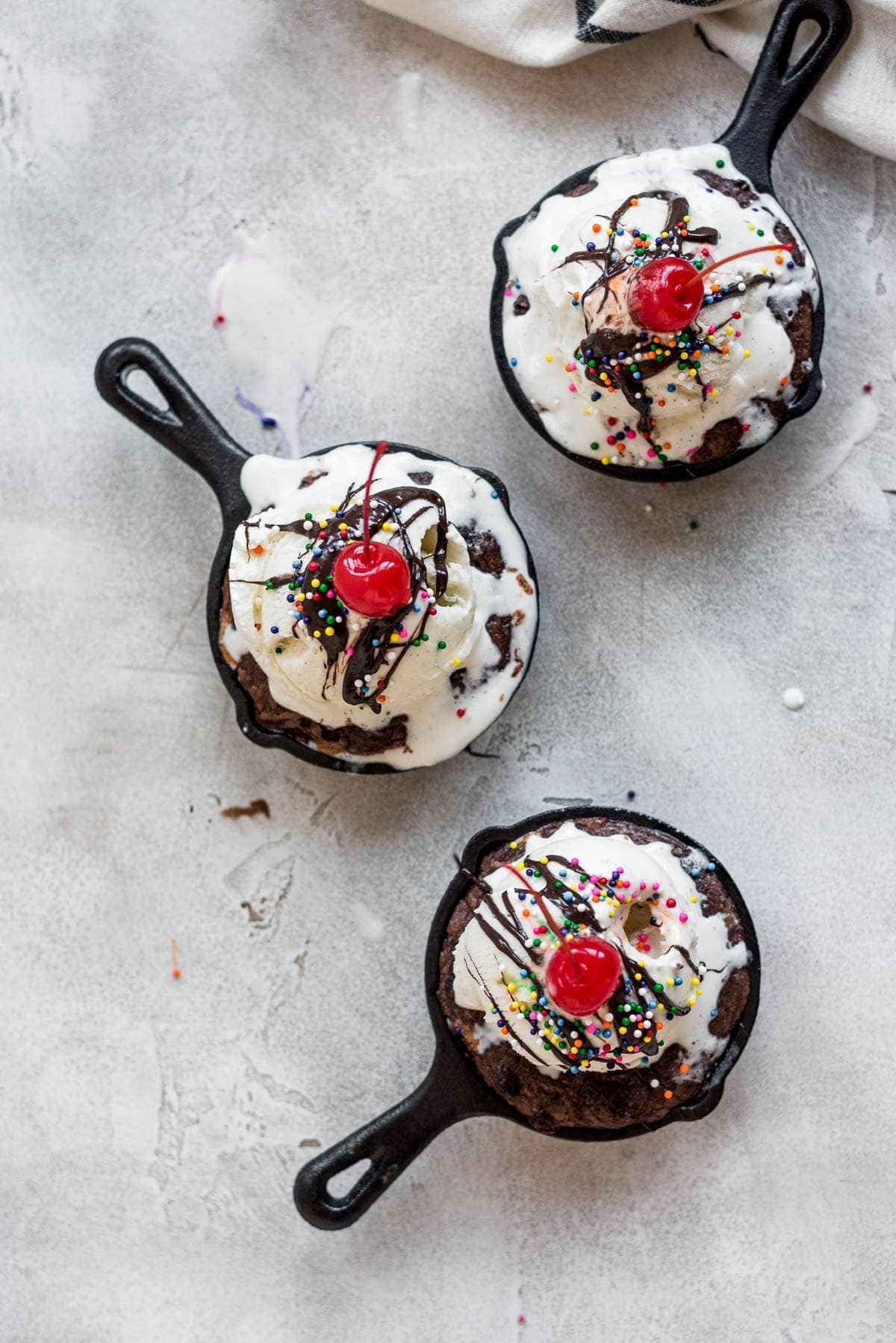 mini skillets topped with ice cream, chocolate syrup, and cherries