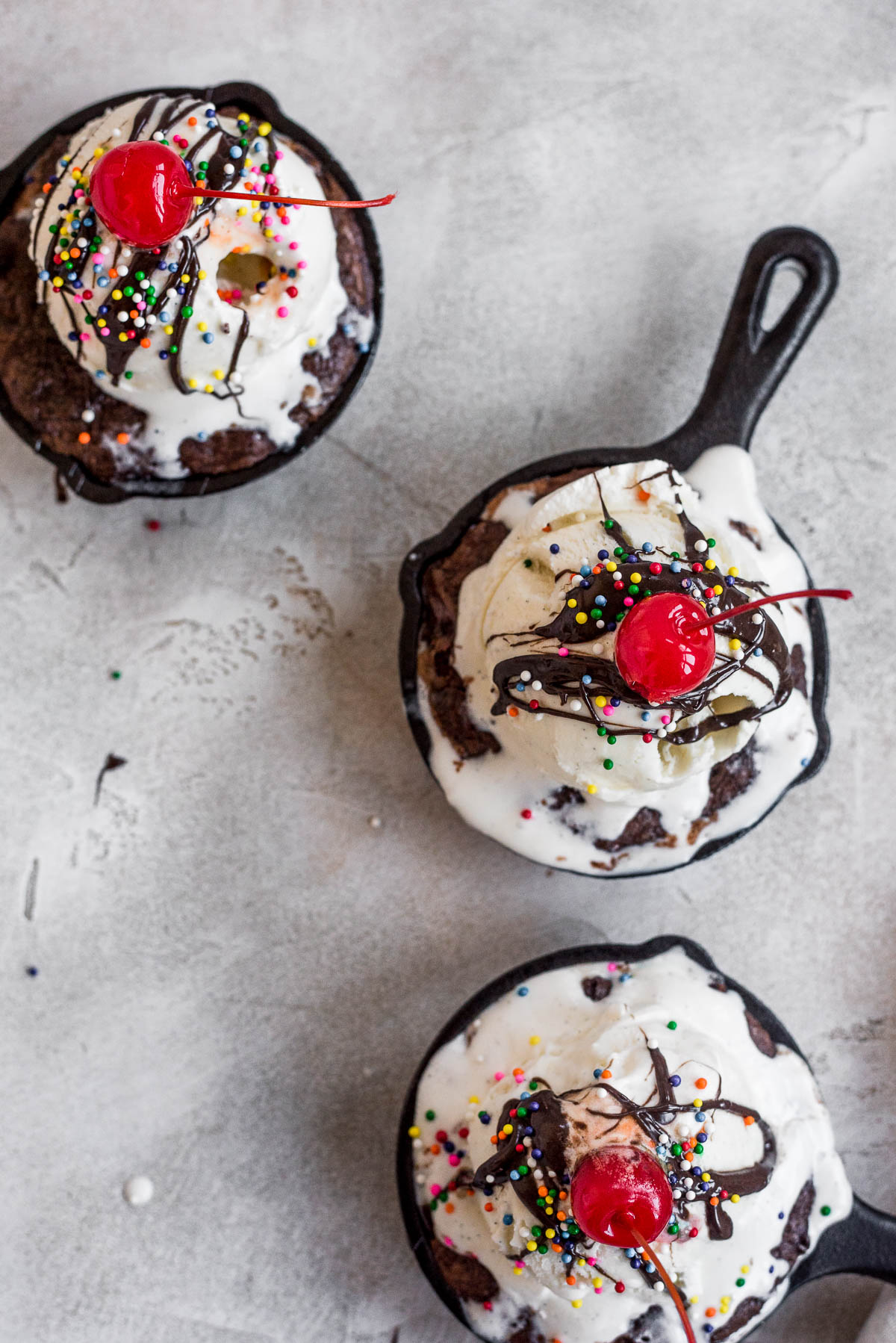 brownies topped with ice cream, chocolate syrup, sprinkles, and cherries