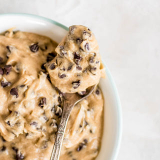 close up cookie dough frosting on spoon over bowl