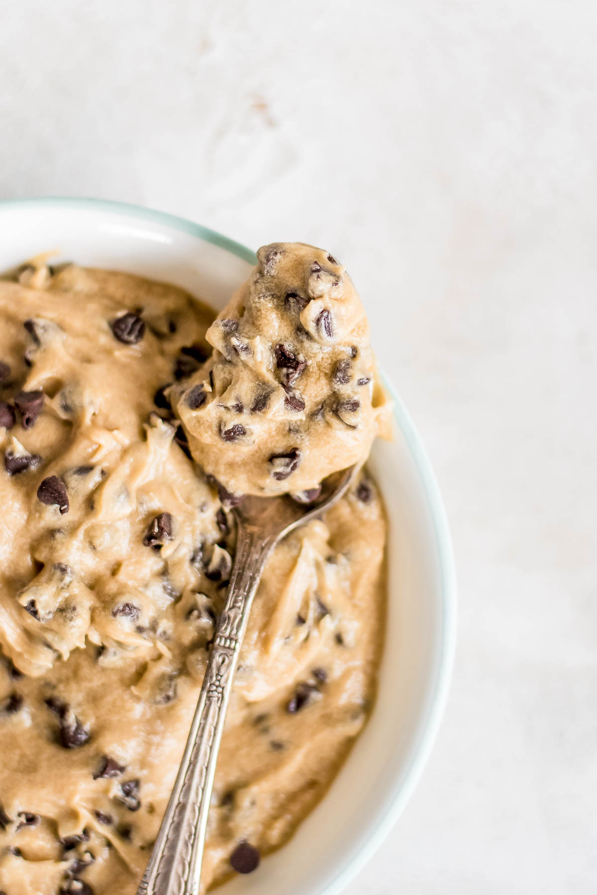 close up cookie dough frosting on spoon over bowl