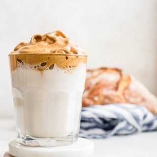 whipped coffee in glass with loaf of bread in background