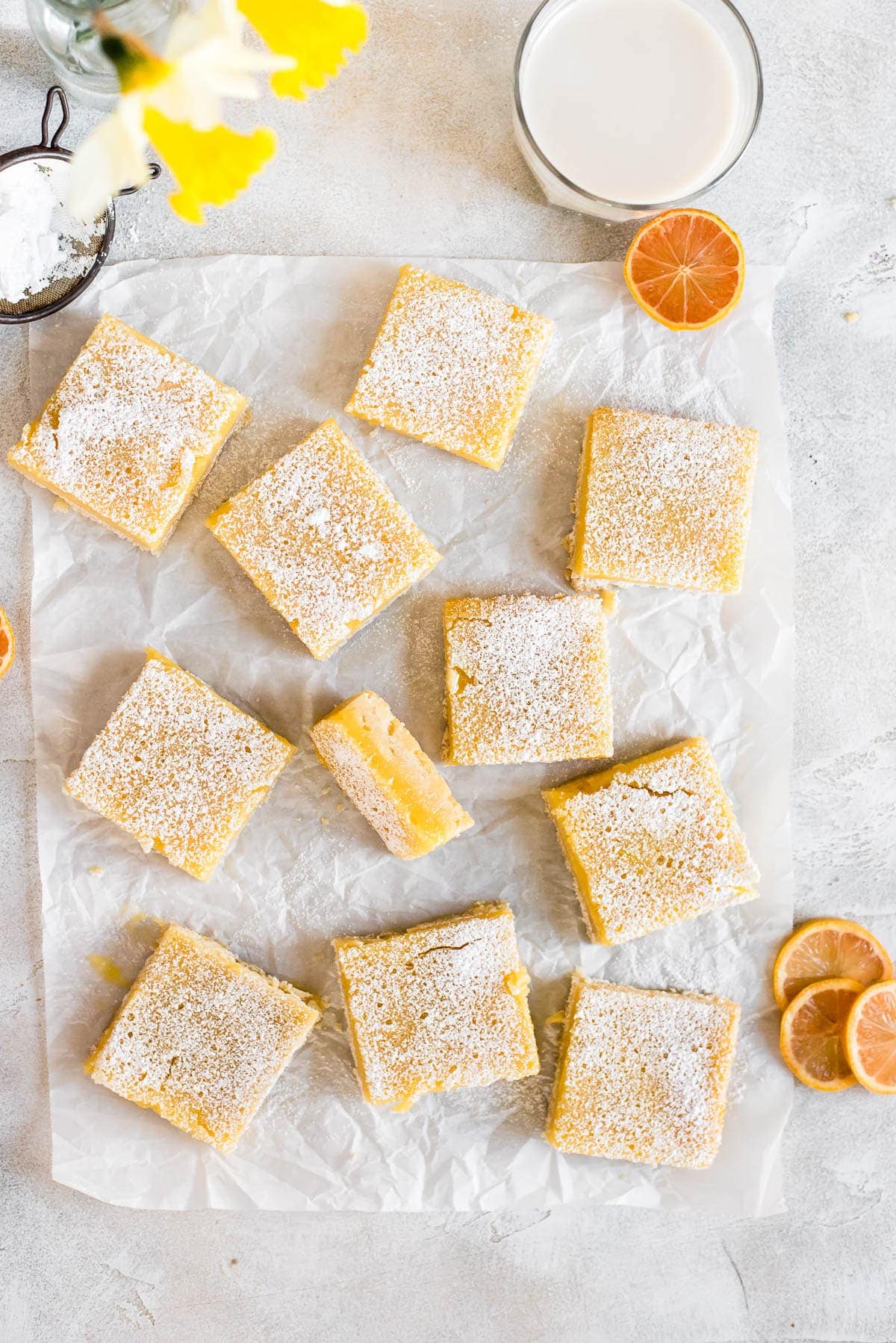 lemon bars on parchment paper dusted with powdered sugar