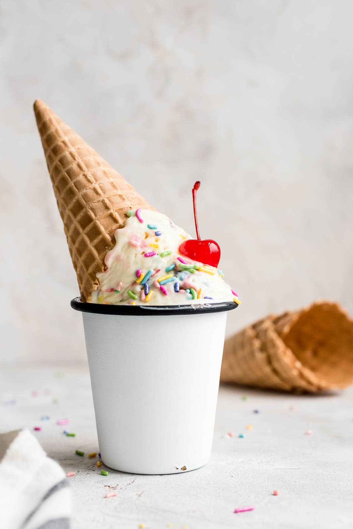 ice cream cone upside down with ice cream in cup with cherry
