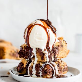 stacked cookie bars topped with ice cream and chocolate sauce
