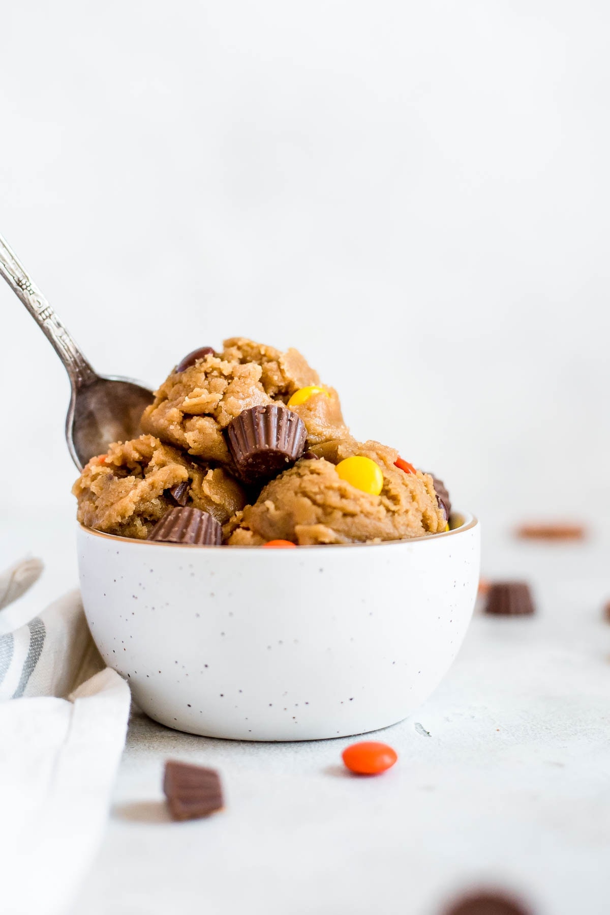 peanut butter cookie dough scooped onto a small white bowl with spoon